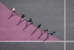 people walking diagonally along a line between grey and lilac colors
