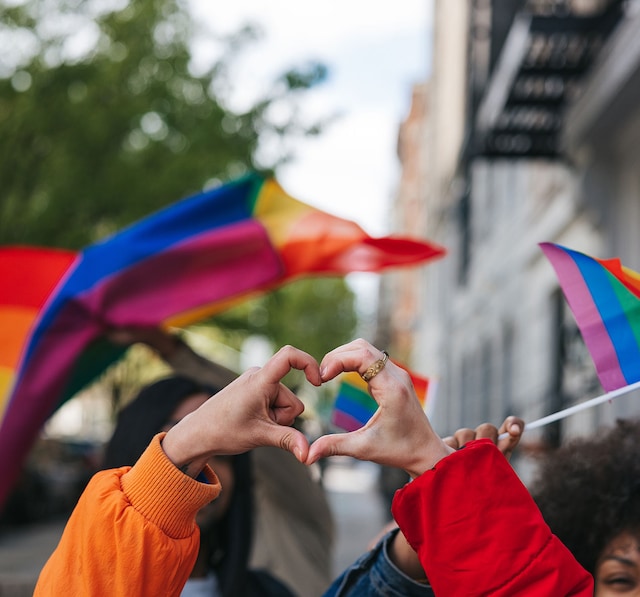 Two hands in a heart with Pride rainbow flags