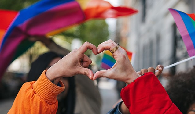 Two hands in a heart with Pride rainbow flags